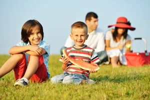 Cheerful children on beautiful summer meadow enjoying and having picnic