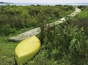 Yellow kayak, upside down, at end of boardwalk to beach-1