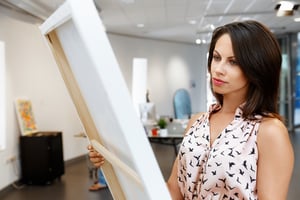 Young caucasian woman standing in art gallery front of  paintings